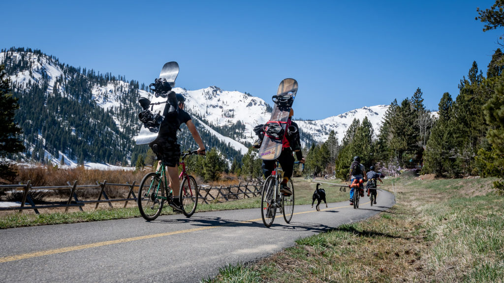 Snowboarders and skiers biking along the Squaw Valley path to The Spring Skiing Capital. 